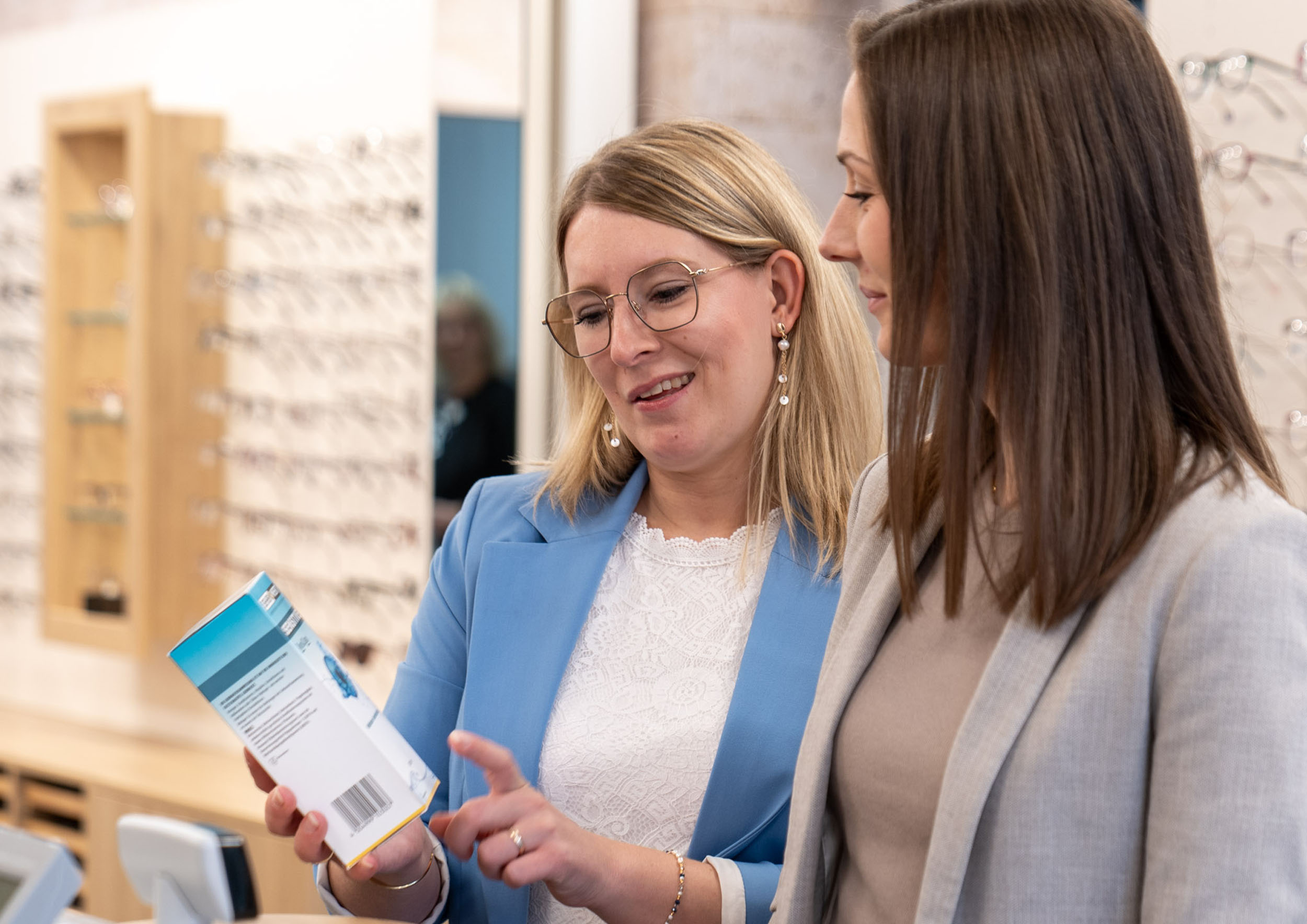 Optikerin erklärt Kundin ein Pflegemittel für Kontaktlinsen